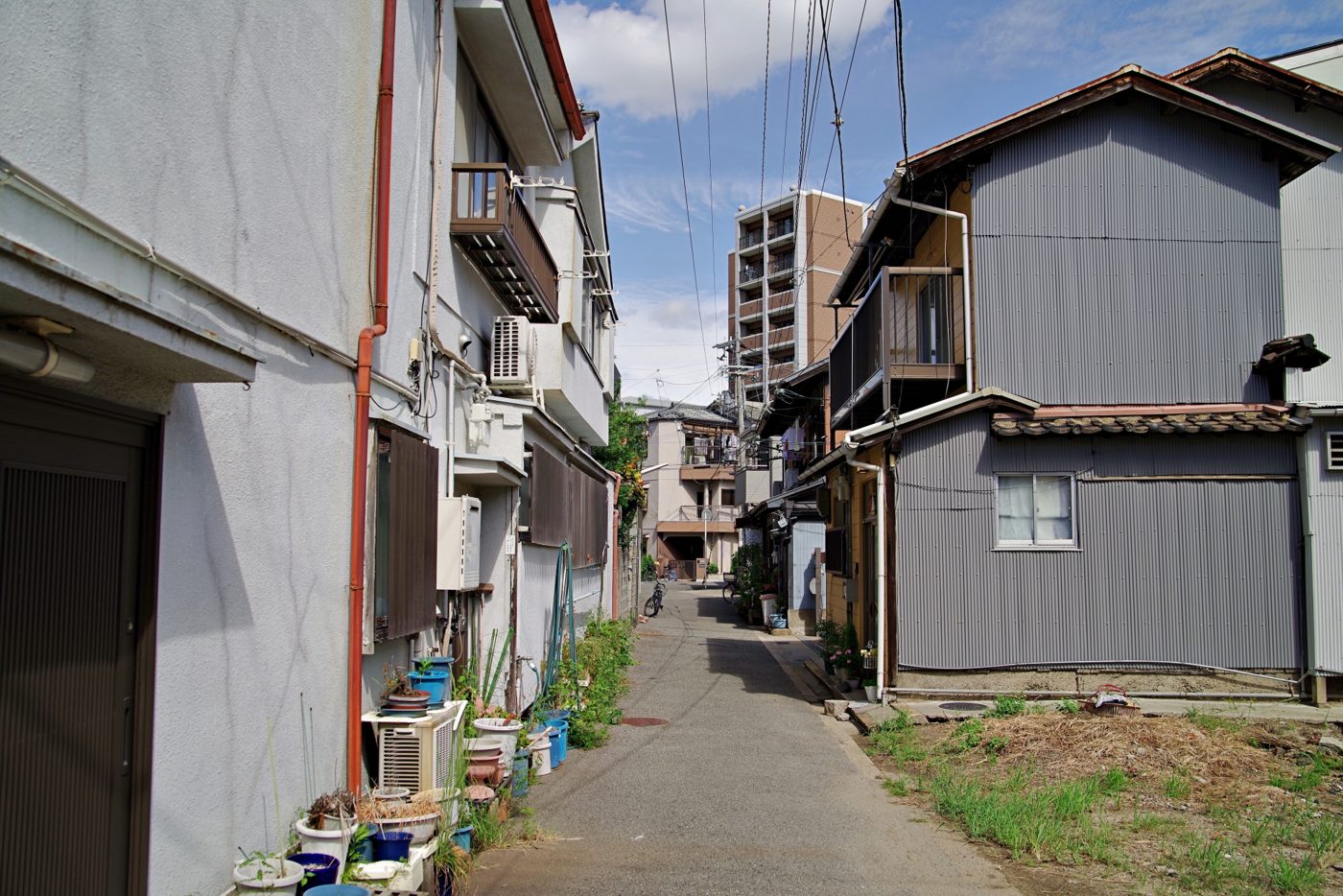 古い木造住宅が向かい合う、舗装された細い生活道路
